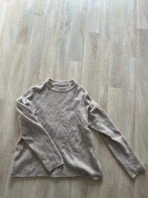 Beige stickad tröja från ONLY - PASSAR S-M med. Mysig beige stickad tröja från ONLY med ribbad struktur och rund hals. Tröjan har långa ärmar och en avslappnad passform som passar perfekt till jeans eller kjol. Enkel och stilren design som funkar till det mesta.