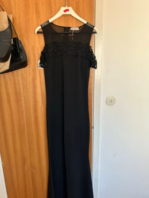Svart långklänning med spetsdetaljer - Svart lång festklänning med off shoulder lace. Köpt i Turkiet för 900kr. Använd endast en gång så skicket är väldigt bra. Sitter jätte fint på kroppen. Stl S men passat lika väl för XS.
