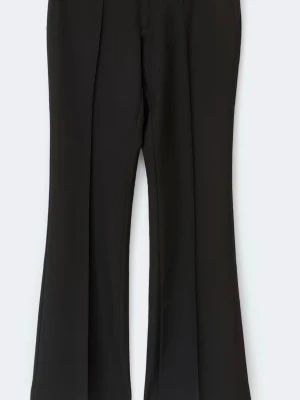 Svarta utsvängda kostymbyxor från Gina - Säljer ett par svarta kostymbyxor med utsvängda ben och pressveck. Byxorna har hög midja och är sydda i ett mjukt, följsamt tyg som ger en snygg siluett. Perfekta för dig som gillar en stilren och trendig look.