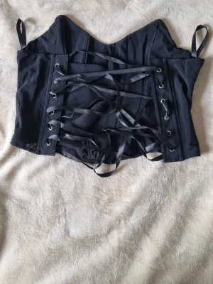 Svart korsett med snörning - Säljer en svart korsett. Har bara provat den så den är i väldigt bra skick. Bild på kommer vid intresse av köpet.