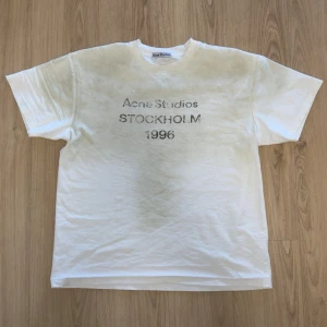 Vit Washed dirt look Acne Studios t-shirt Stockholm - Vit t-shirt från Acne Studios med trycket 'Acne Studios STOCKHOLM 1996' på bröstet. Klassisk passform med rund hals och korta ärmar. Perfekt basic-plagg med clean look och diskret logga framtill.
