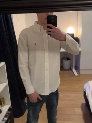 Vit skjorta från Ralph Lauren - Klassisk vit skjorta från Ralph Lauren med broderad logga på bröstet. Skjortan har lång ärm, knappar framtill och en snygg krage. Perfekt för en clean och stilren look. Storlek 10 motsvarar s. Perfekt för sommar och vår