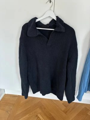 Mörkblå stickad tröja med krage - Mysig mörkblå stickad tröja med bred krage och v-ringning. Tröjan har lång ärm och ribbade muddar vid ärmslut och nederkant. Perfekt för lager-på-lager och chill stil. .