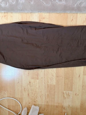 Brun långklänning från Bershka - Snygg brun långklänning från Bershka i mjukt material. Klänningen har en enkel och stilren design utan mönster eller detaljer, perfekt för dig som gillar minimalistisk stil. Passar till många olika looks och är lätt att styla.