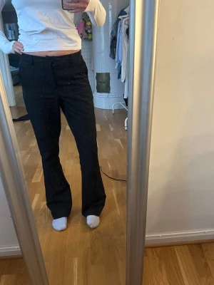 Svarta kostymbyxor - Säljer ett par svarta kostymbyxor med rak passform och normal midja. Byxorna har klassisk look med diskreta fickor och är perfekta för en clean och stilren outfit. Materialet ser ut att vara en mjuk och följsam textil som ger en snygg siluett.