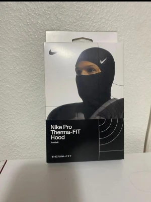 Nike Pro Therma-FIT Hood svart - Nike Pro Therma-FIT Hood är en svart huva designad för att hålla värmen under kalla dagar. Tillverkad i ett stretchigt och värmeisolerande material som sitter tight runt huvudet. Perfekt för träning utomhus eller som extra lager under hjälm.