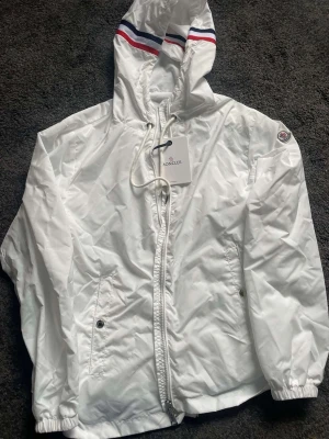 Vit vindjacka från Moncler - Riktigt snygg moncler windbreaker. Skick:10/10 inga problem✅. Storlek M passar perfekt. Nfc scan på loggan och qr kod 