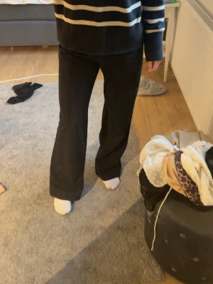 Svarta vida kostymbyxor - Säljer ett par svarta kostymbyxor med hög midja och raka, vida ben. Byxorna har en klassisk look och passar perfekt till en snygg outfit. Materialet ser ut att vara en mjuk och följsam blandning, vilket gör dem bekväma att bära hela dagen.