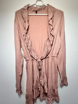 Lång kofta - Längre rosa kofta ifrån märket Soyaconcept i storlek XL🌷 - Volanger krage som följer längs med koftans Öppning samt volanger vid ärm slut - Knytband i midjan - 75% viscose, 25% nylon