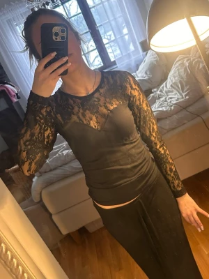 Svart spetströja - Snygg svart tröja i spets med långärmad design och transparenta partier. Toppen har en figurnära passform och rund halsringning. Perfekt för dig som vill ha en trendig och elegant look. Tröjan är i storlek m men passar även mig i xs tröjan är stretchig 