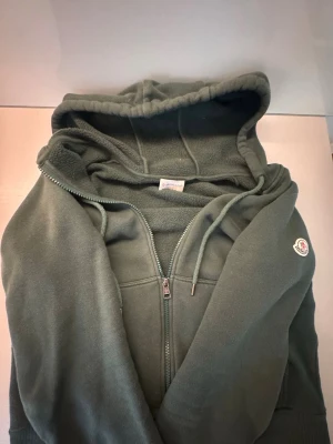 Moncler Hoodie - Riktig snygg Mörkgrön Moncler hoodie. Garanterad äkthet. Ny pris ca 6000kr. Storlek M fast passar S. 8/10 skick, ett litet hål vid vänstra fickan. DMa för fler bilder eller frågor!