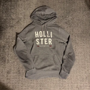 Grå hoodie från Hollister - Hollister tröja i storlek L. Den har en fläck på bröstet men går säkert bort med lite galltvål.