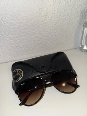 Ray-Ban bruna solglasögon aviator - Snygga Ray-Ban solglasögon i klassisk aviator-modell med bruna bågar och mörka glas. Kommer med original svart fodral i skinnimitation. Perfekta för soliga dagar och ger en tidlös look. Varför jag säljer är för att jag tycker inte detta är en modell för mig helt enkelt. Pris kan diskuteras! 