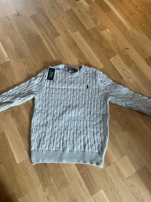 Ljusgrå kabelstickad tröja Polo Ralph Lauren - Kabelstickad tröja i ljusgrått från Polo Ralph Lauren S