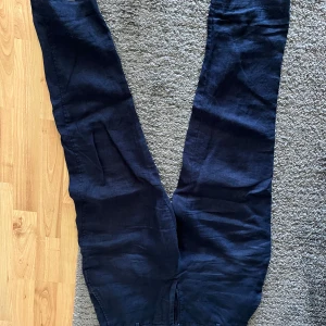 Mörkblå linnebyxor från Zara - Snygga mörkblå linnebyxor från Zara med elastisk midja för extra komfort. Perfekta för en avslappnad stil med en touch av elegans. Byxorna har en rak passform och är tillverkade i ett lätt och luftigt material.
