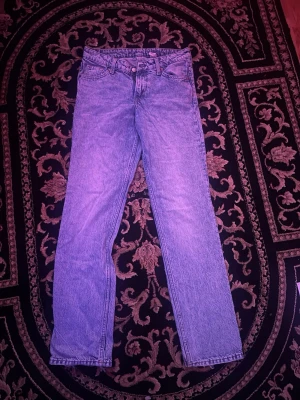 Blå raka jeans i denim - Säljer ett par klassiska blå raka jeans i denim med låg midja och regular fit. Perfekta för en avslappnad och tidlös stil.