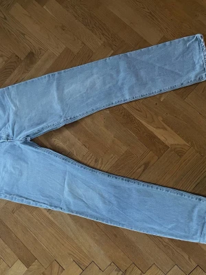 Ljusblå raka Levi's 501 jeans - Säljer ett par klassiska ljusblå Levi's 501 jeans med rak passform och hög midja. Jeansen har fem fickor, bälteshällor och den ikoniska läderlappen bak i midjan. Tillverkade i slitstark denim, perfekta för en avslappnad och tidlös stil.