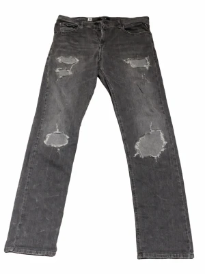 Grå slitna jeans med raka ben - Snygga grå jeans med slitningar och hål på båda ben. Jeansen är från replay. Storlek W32 L34. Kan gå ner i pris vid snabb affär.