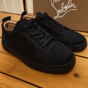 Mörkblå sneakers från Louboutin - Skickar inom 24h och godkänner dom flesta erbjudanden. Tja jag säljer dessa snygga mörkblå sneakers från Christian Louboutin i mocka med matchande mörkblå snörning och diskret broderad logga på hälen. Skorna har en låg siluett och svart sula för en clean och stilren look. Perfekta för dig som gillar exklusiva och trendiga sneakers. 