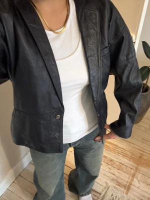 Svart vintage skinnjacka  - Säljer min super snygga svarta skinnjacka i blazer-modell från Läder AB. Jackan har klassisk krage, knappstängning och fickor fram. Köpte den på en märkes vintage butik i Italien, nypris ca 1600 kr