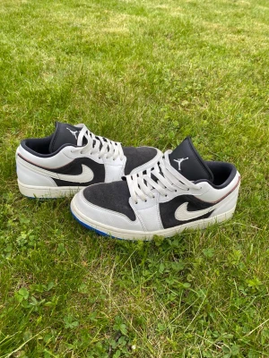 Air Jordan 1 Low svart/vit - Säljer ett par Air Jordan 1 Low sneakers i svart mocka och vitt med blå yttersula. I väldigt bra skick! Fråga gärna om du har några frågor.