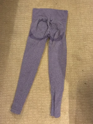 Lila sömlösa leggings - SKULLE GISSA PÅ STORLEK M!Snygga lila leggings med hög midja och sömlös design. De har diskreta konturdetaljer runt höften och är tillverkade i ett stretchigt material som sitter tajt mot kroppen. Perfekta för träning eller chill dagar.