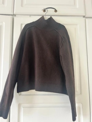 Mörkbrun stickad polotröja💖💖 - Mysig mörkbrun stickad tröja med hög ribbad polokrage och långa ärmar. Tröjan har breda ribbade muddar vid ärmslut och nederkant, vilket ger en snygg och avslappnad look. Perfekt för kyliga dagar och enkel att matcha med jeans eller kjol.