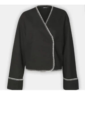 Svart omlottkofta med vit kant - Sitter som en S-M faktsikt Stilren svart omlottkofta med vita dekorativa sömmar längs kanterna och ärmsluten. Säljer billigt för ena knappen är av och andra fungerar ej🥰går att använda som en kofta!