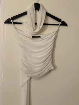 Vit topp med scarf från Gina  -  Vit topp med scarf från Gina tricot strl S. Toppen har en snygg extra scarf-detalj och är tillverkad i ett lätt, transparent material som ger en luftig känsla. Aldrig använd 