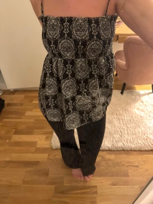 Mörkbrun mönstrad linnetopp  - Vintage-liknande linnetopp i mörkbrunt och beiget mönster och tunna axelband. Dekorativa paljettdetaljer framtill. Säljs inte längre ❤️ så fin på sommaren! 