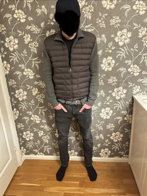 Grå Moncler cardiganjacka - Snygg grå cardiganjacka från Moncler med quiltad front och ärmar i mjukt stickat material. Jackan har dragkedja framtill, ståkrage och diskret Moncler-logga på ärmen. Perfekt för lager-på-lager och streetwear-stil.