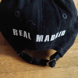 3 st Real Madrid kepsar 2 st  från Adidas 150 kr st. - 140  kr st eller 400  kr för alla 3 st  Real Madrid kepsar i svart och vitt med broderat klubbmärke framtill och texten 'REAL MADRID' baktill. Justerbar rem med metallspänne. Kepsen är tillverkad i bomull och har vita kontrastsömmar. Perfekt för dig som älskar fotboll och vill visa ditt stöd för Real.