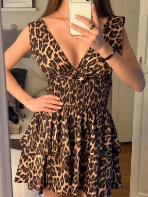 Leopardmönstrad kort klänning - Snygg kort klänning med leopardmönster och djup v-ringning och öppen rygg. Man kan ha den på två sätt !