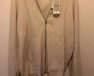 Beige hoodie från Jack & Jones - Säljer en beige hoodie från Jack & Jones i storlek XL. Hoodien har dragkedja framtill, två stora fickor och en klassisk huva. Tillverkad i mjukt material som känns skönt mot huden. Perfekt för en avslappnad och stilren look. Helt ny med prislapp! 