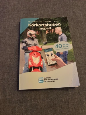Körkortsboken moped STR - Körkortsboken för moped från STR, med 40 extra sidor om A-traktor och mopedbil. Boken har färgtryck och ett omslag med bilder på moped och mobiltelefon. Perfekt för dig som pluggar till moppekörkort.