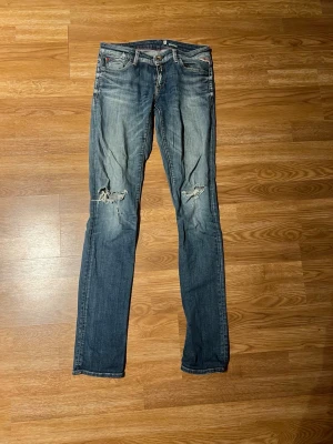 Blå slitna jeans med hål - Säljer ett par blå jeans med slitningar på båda knäna. Jeansen har raka ben, klassisk femficksmodell och random faded effekt framtill or back. Perfekta för en som vill klä sig med stil och pondus! PRIS kan diskuteras!