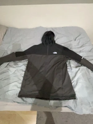 Svart hoodie från The North Face - Säljer en svart hoodie från The North Face med dragkedja halvvägs ner och klassisk logga på bröstet. Hoodien har en huva och är tillverkad i ett mjukt, funktionellt material. Perfekt för dig som gillar streetwear och sportig stil.