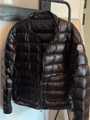 Svart dunjacka från Moncler - Snygg svart dunjacka från Moncler med glansig finish och klassisk quiltad design. Kvitto finns ej, men alla tags är kvar och scan fungerar.