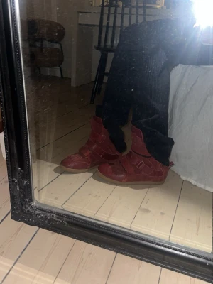 Röda höga sneakers med kardborre - Unika röda sneakers med högt skaft och tre breda kardborreband. Skorna har en chunky sula och är tillverkade i ett material som ser ut som mocka. Perfekta för dig som vill sticka ut med en cool och retro vibe. Har använt typ 2,3 gånger 