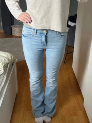 Ljusblå bootcut jeans - Säljer ett par ljusblå bootcut jeans med klassisk femficksmodell och normal midja. Jeansen har en snygg tvätt och lätt utsvängda ben, perfekta för en avslappnad och trendig look. Tillverkade i mjukt denimtyg som sitter skönt hela dagen.