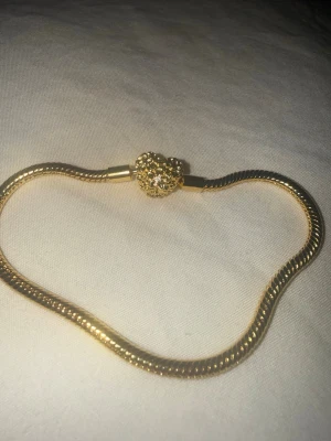 Pandora berlockarmband - Snyggt armband från Pandora med ett hjärtlås i mitten. Armbandet har en ormlänkskedja som ger en modern och stilren look. Perfekt accessoar för att lyfta din outfit.