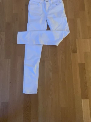 Vita Levi's 710 Super Skinny jeans - Säljer ett par vita Levi's 710 Super Skinny jeans med tight passform och klassisk femficksdesign. Jeansen har låg midja och är tillverkade i stretchigt material för en bekväm känsla. Perfekta för dig som gillar en slimmad siluett.