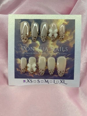 SoftLeo (XS);Medium Almond - Snygga handgjorda press-on naglar i beige nyans med leopardmönster och glansig finish. Några naglar har dekorativa vita 3D-blommor. Naglarna är medium långa och har en almond-form. Perfekt för dig som vill ha något unikt och trendigt.XS: 14 mm, 11 mm, 11,5 mm, 10 mm, 8 mm 