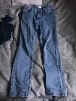 Ljusblå grunt jeans - Säljer ett par ljusblå grunt jeans med klassisk femficksdesign och normal midja. Jeansen har raka ben och är tillverkade i ett mjukt denimtyg som ger en avslappnad look. Perfekta för dig som gillar retrostil och vill ha ett par bekväma jeans till vardags.