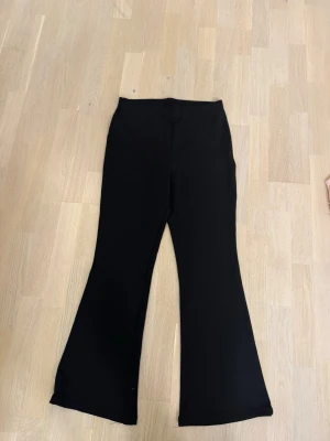 Svarta bootcut leggings från H&M - Säljer ett par svarta leggings från H&M i storlek M. De har bootcut-modell med utsvängda ben och är tillverkade i ett stretchigt material av polyester och elastan. Perfekta för en trendig och bekväm look.