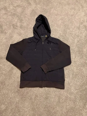 Ralph lauren cardigan mörkblå (180cm) -  Snygg mörkblå cardigan från Ralph Lauren i storlek L. Klassisk och tidlös modell som passar perfekt till både vardag och mer uppklädda outfits. Väldigt lätt att matcha med jeans, chinos eller över en skjorta.  Storlek L och sitter bra på mig som är ca 180 cm.  Cardiganen är lätt solblekt på vissa ställen, men är annars i väldigt bra skick utan hål eller större slitningar. Fortfara