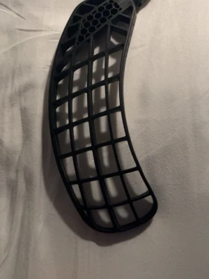 Innebandyblad svart från fatippe en bit skaft sitter kvar Right vänd. - Säljer ett svart innebandyblad från Unihoc med rutnätsdesign och lätt böjd form. Tillverkat i slitstark plast, perfekt för dig som vill ha bra bollkontroll och skott. Passar till de flesta innebandyklubbor med standardfäste.