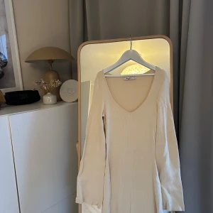 Beige ribbad långklänning - Trendig beige långklänning med v-ringning och långa ärmar. Klänningen är ribbad och har en smickrande passform som passar perfekt till olika tillfällen. Enkel men stilren design som är lätt att matcha med accessoarer. Superfin nu i vår och sommar. Aldrig använd. Passar mig som brukar ha både M och S. Passar även större