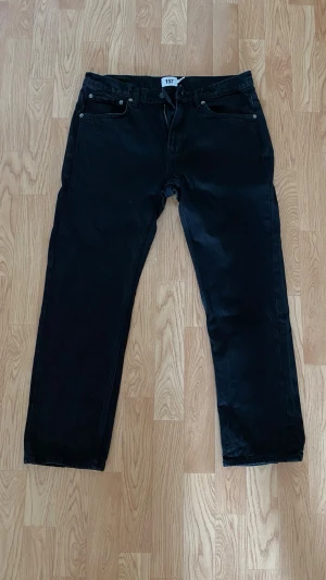 Svarta jeans Lager 157 - Ett par svarta jeans från Lager 157 med rak passform. Klassisk femficksmodell och normal midja. Jeansen har en enkel och stilren look som passar till det mesta. Perfekta för dig som gillar en clean och avslappnad stil.