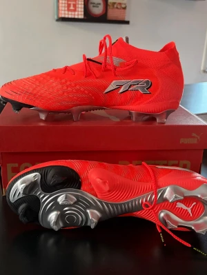 Puma Future 9 Helt Nya - Säljer ett par grymma Puma Future 9 fotbollsskor i en riktigt snygg röd färg med silvriga och svarta detaljer. Skorna är helt nya och kostar 2000 på unisport.